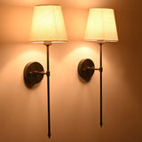 Angled pair of Milan ivory shade wall sconces with black rod frames and warm evening lighting.
