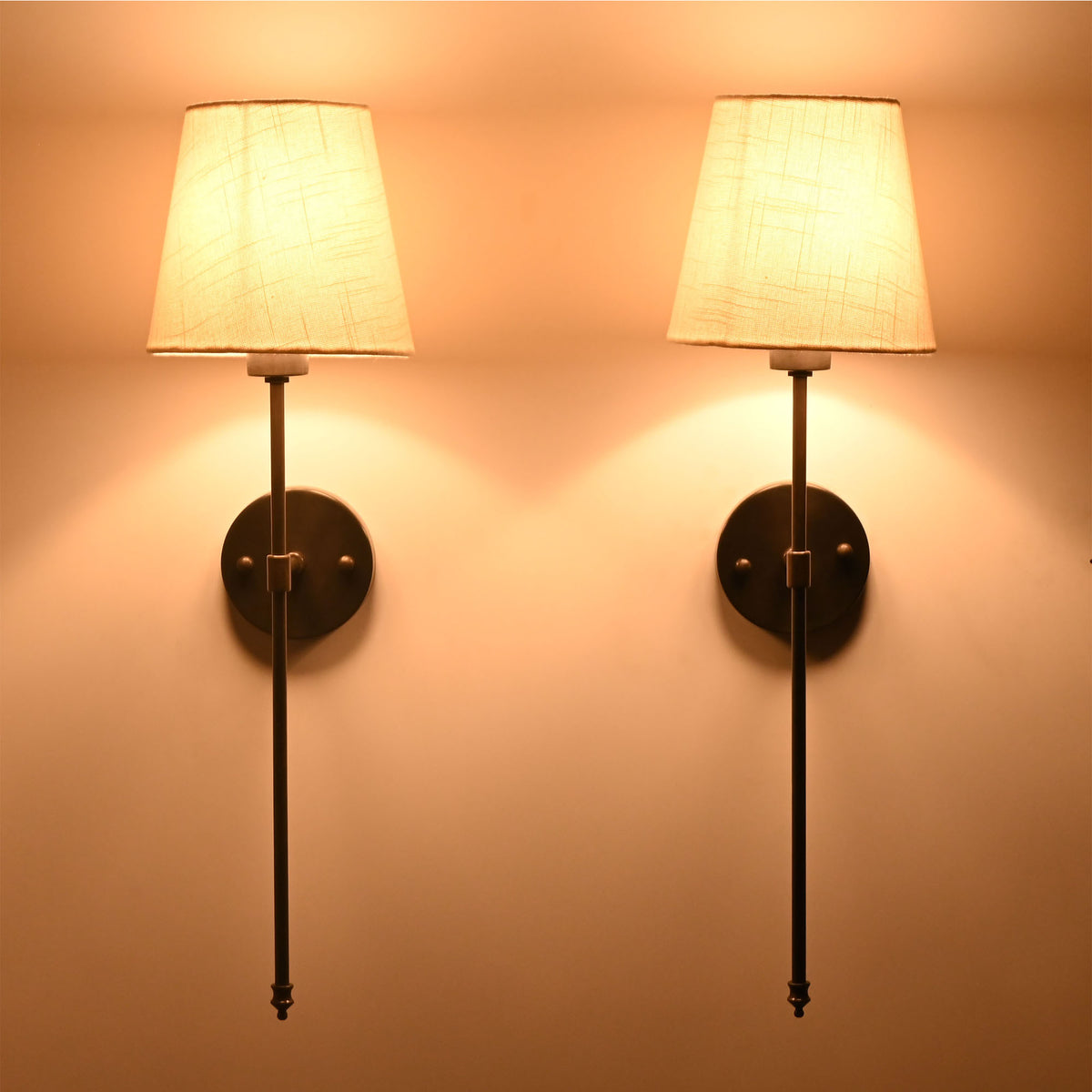 Ivory shade black rod wall sconces glowing warmly with soft diffused light and elegant wall presence.
