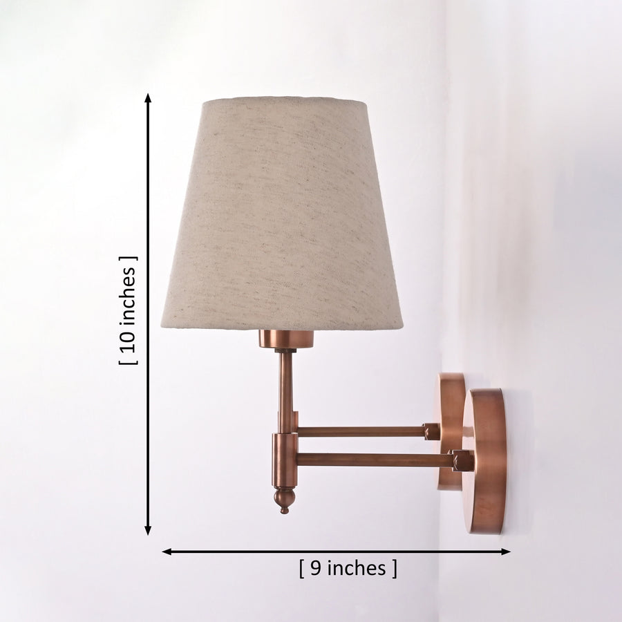 Two Milan copper antique brass wall sconces with natural linen fabric shades installed on either side of framed artwork above a wooden console table, creating a warm and elegant entryway with soft ambient lighting.