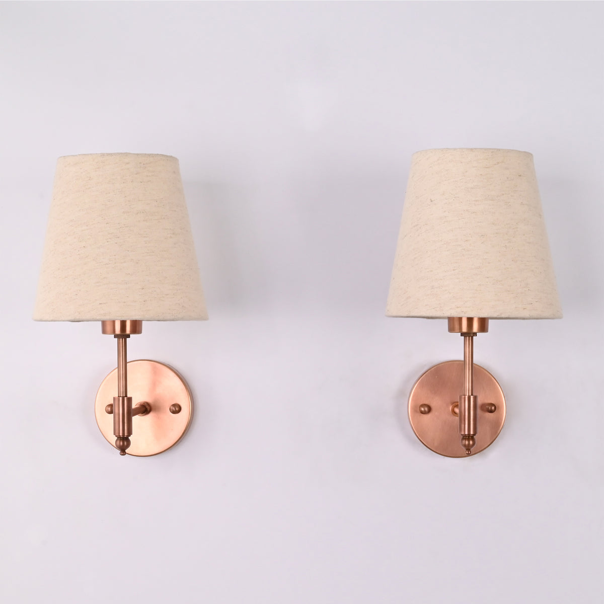 Handcrafted Milan copper antique solid brass wall sconce with a natural linen tapered fabric shade shown in a straight front view, featuring a round backplate and compact modern transitional design.