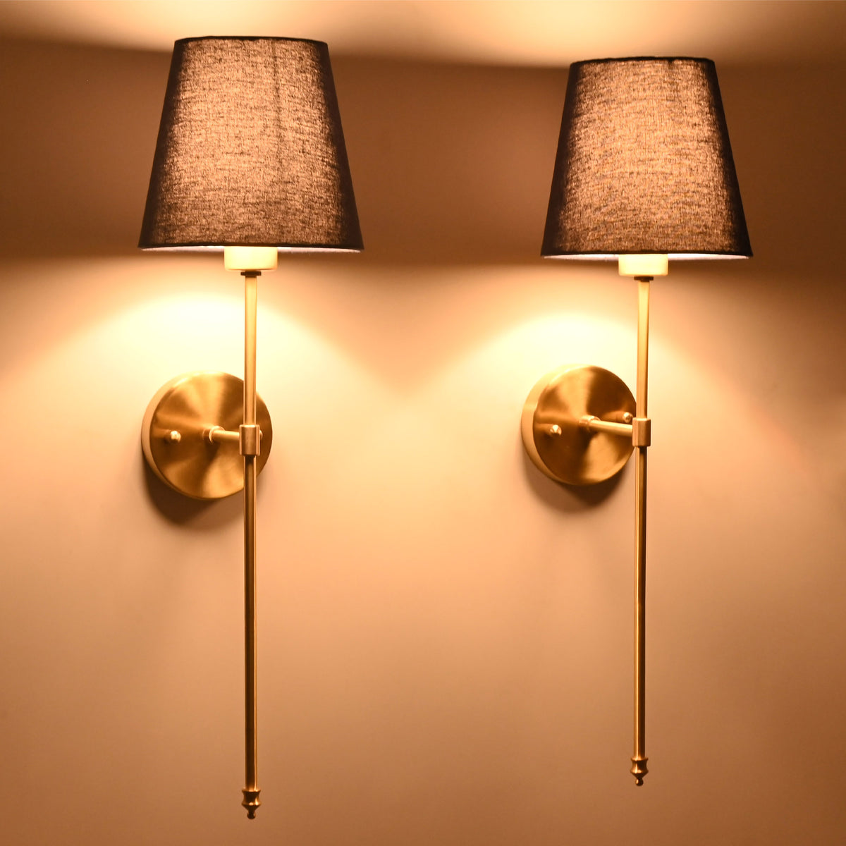 Pair of illuminated navy shade wall sconces creating warm ambient glow with refined classic styling.