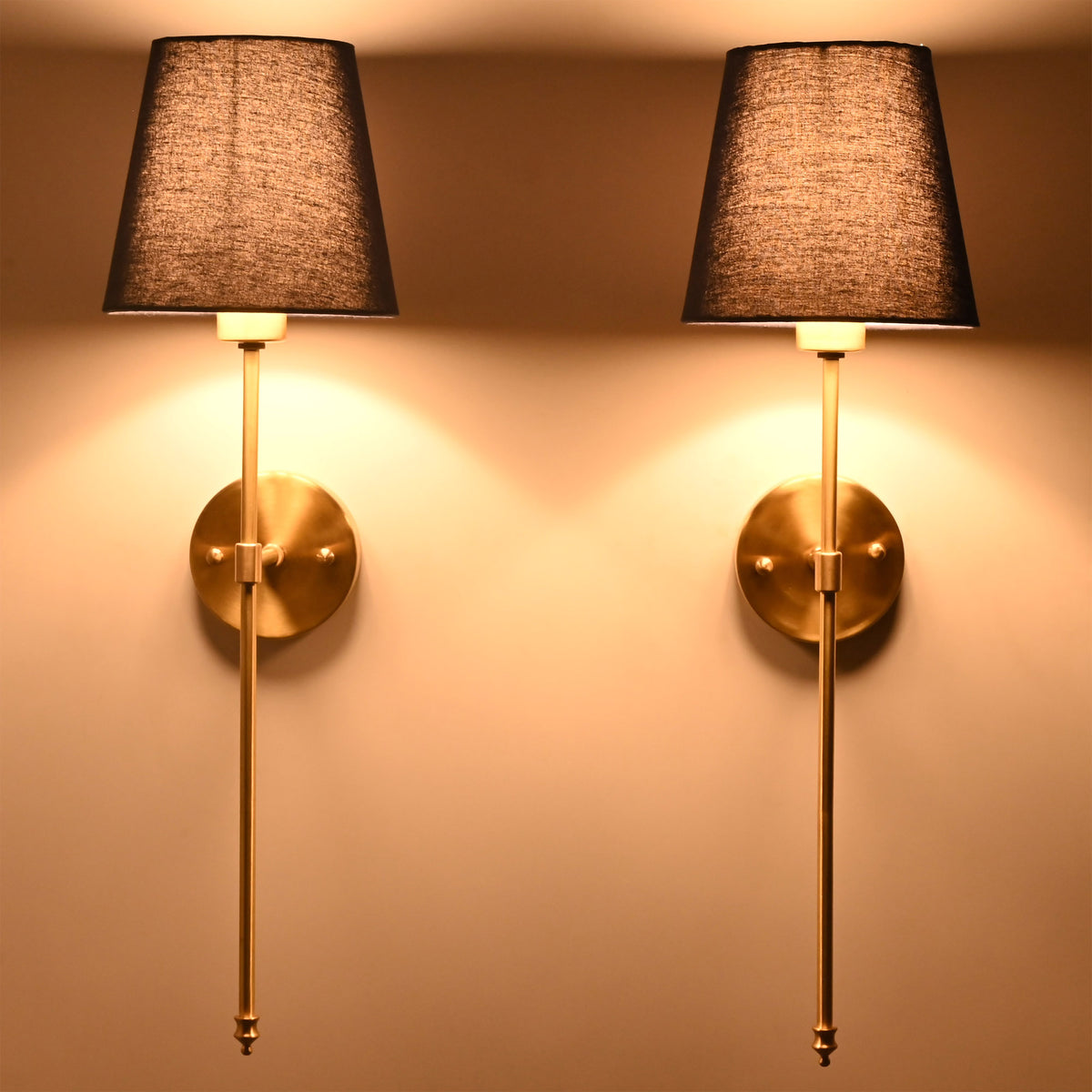 Milan navy shade wall sconces glowing warmly with tall rod frames and soft wall illumination.