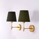 Pair of Milan brushed brass wall sconces with olive green tapered fabric shades shown from an angled perspective, highlighting the elegant brass finish.