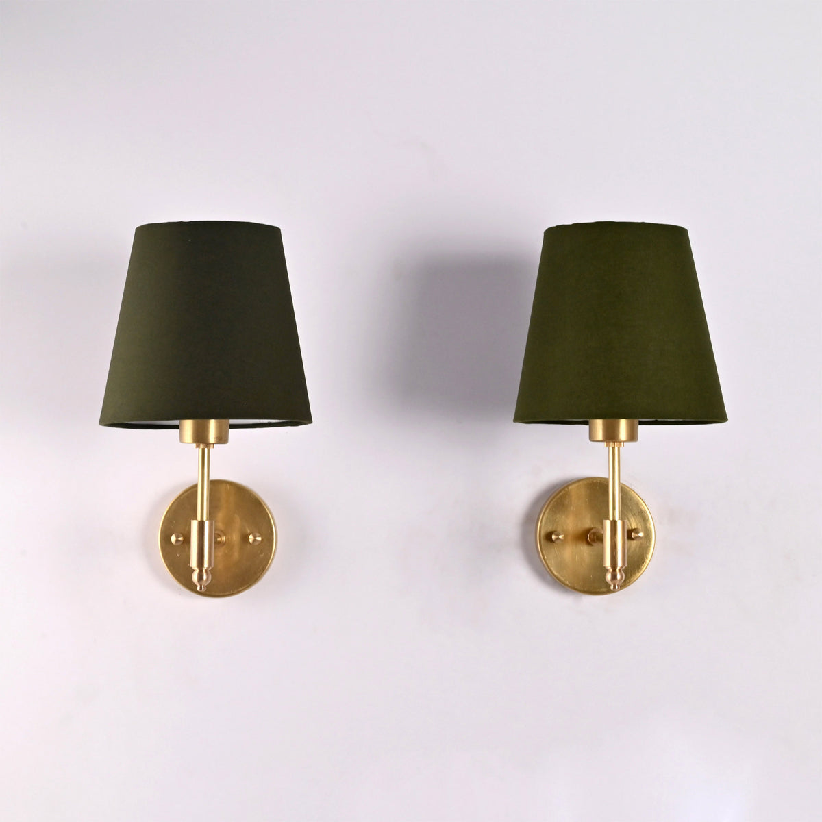 Front view of the Milan olive green fabric shade brushed brass wall sconce featuring a handcrafted solid brass frame and round wall backplate.