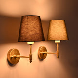 Perspective view of illuminated Milan olive green fabric shade brushed brass wall sconces highlighting handcrafted brass construction and soft lighting.