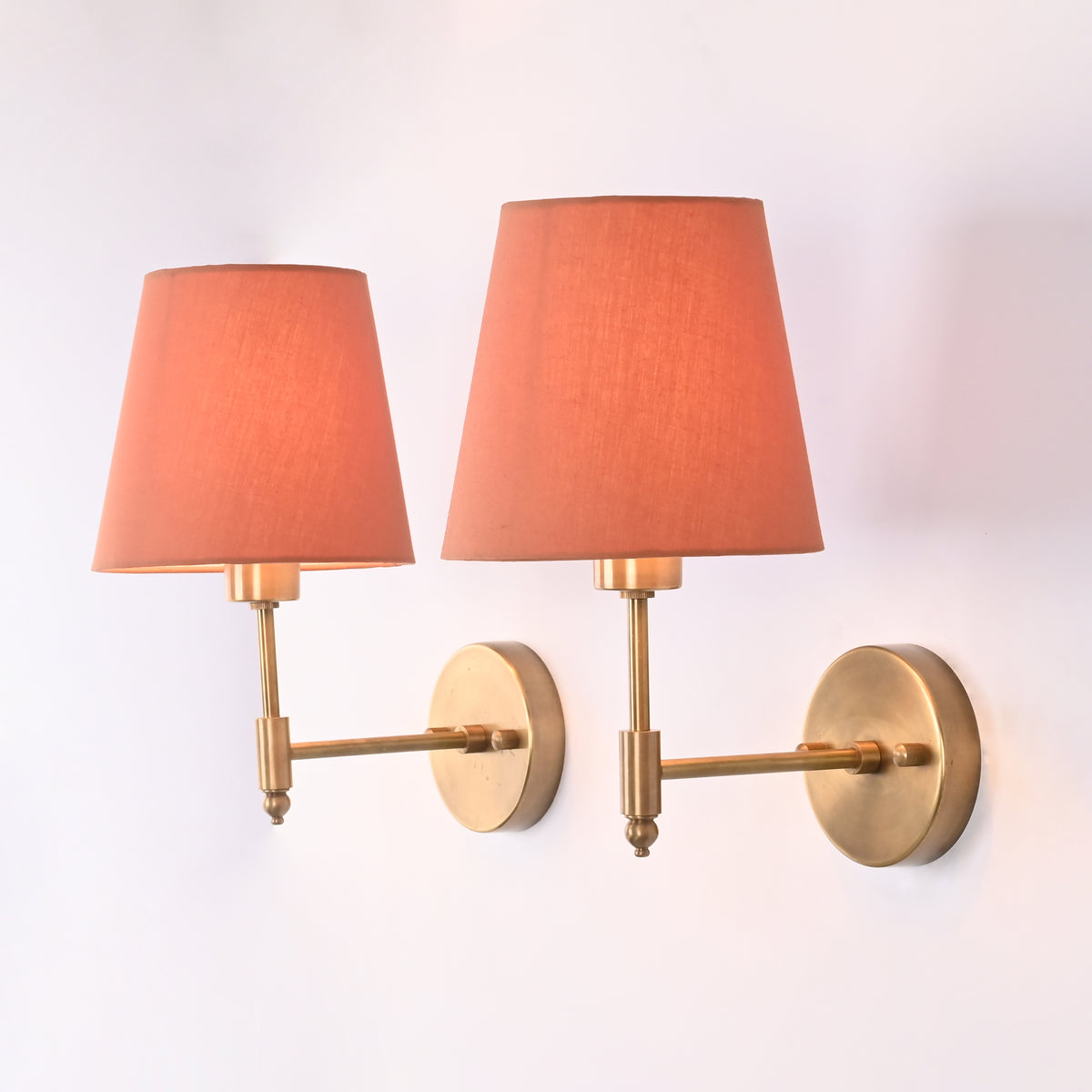 Side angle of Milan Peach Shade Antique Brass Short Wall Sconce showing its 9-inch projection, antique brass arm, and peach fabric shade.