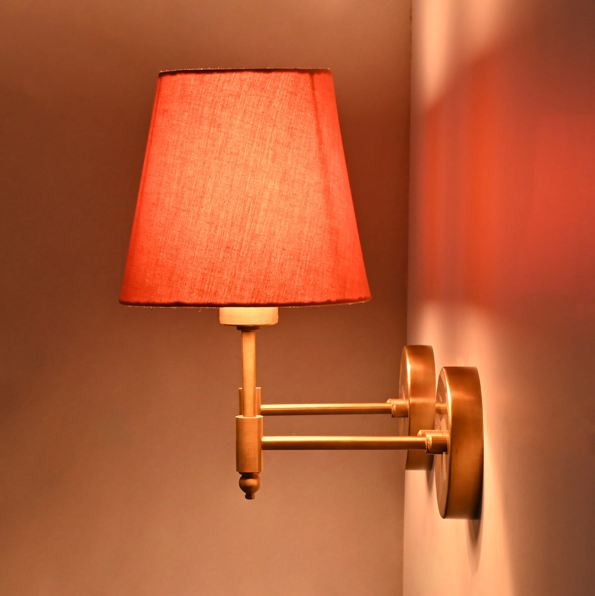 Pair of illuminated Milan Peach Shade Antique Brass Short Wall Sconces creating elegant warm accent lighting.