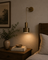 Milan pulley cylinder 1 light wall sconce in brass installed beside a bed with warm ambient lighting