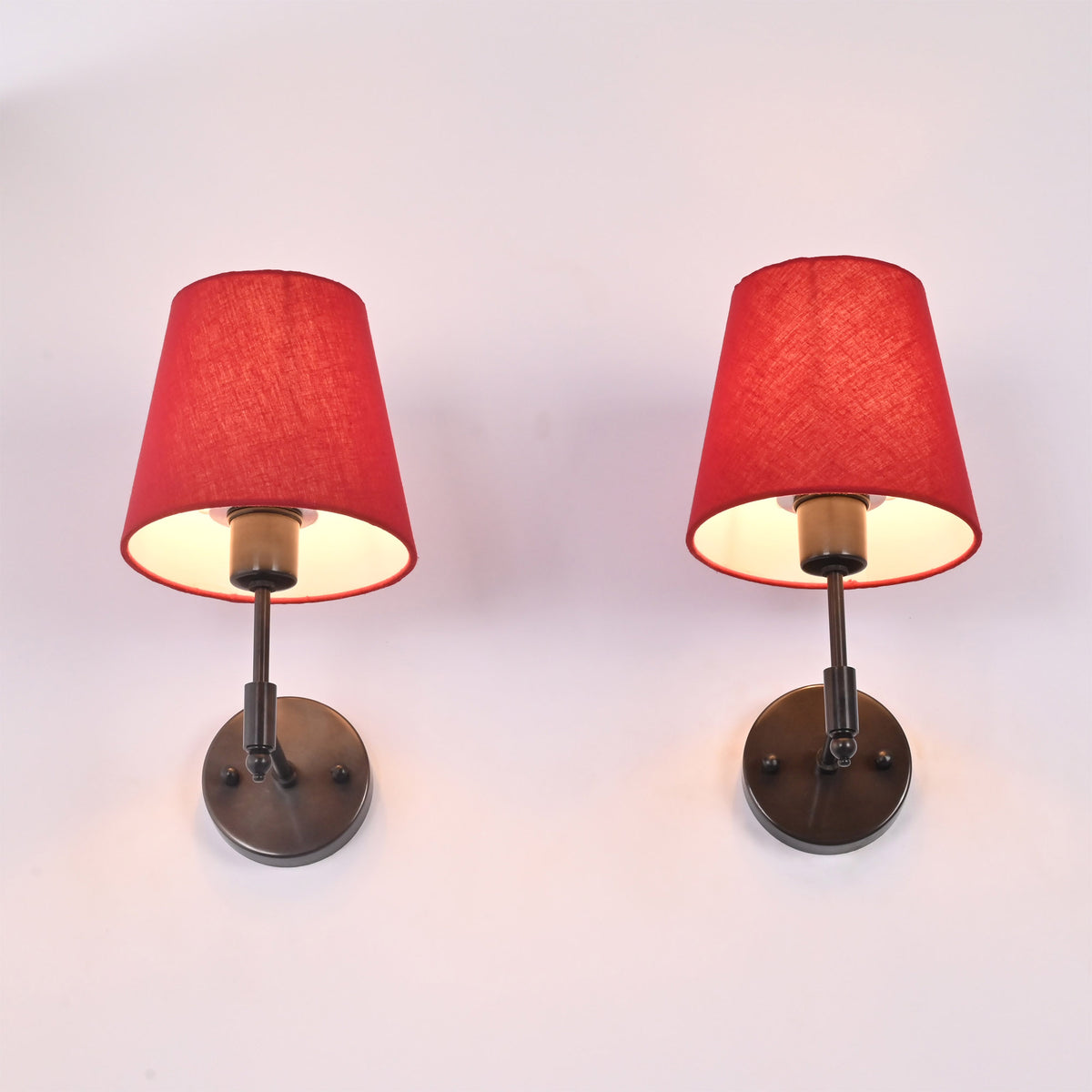 Angled upward view of Milan red shade black wall sconce pair showing warm light under tapered shades.