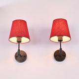 Angled upward view of Milan red shade black wall sconce pair showing warm light under tapered shades.