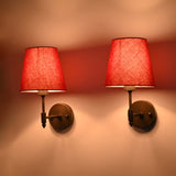 Close side illuminated view of Milan red shade black wall sconce with compact arm and warm red shade glow.
