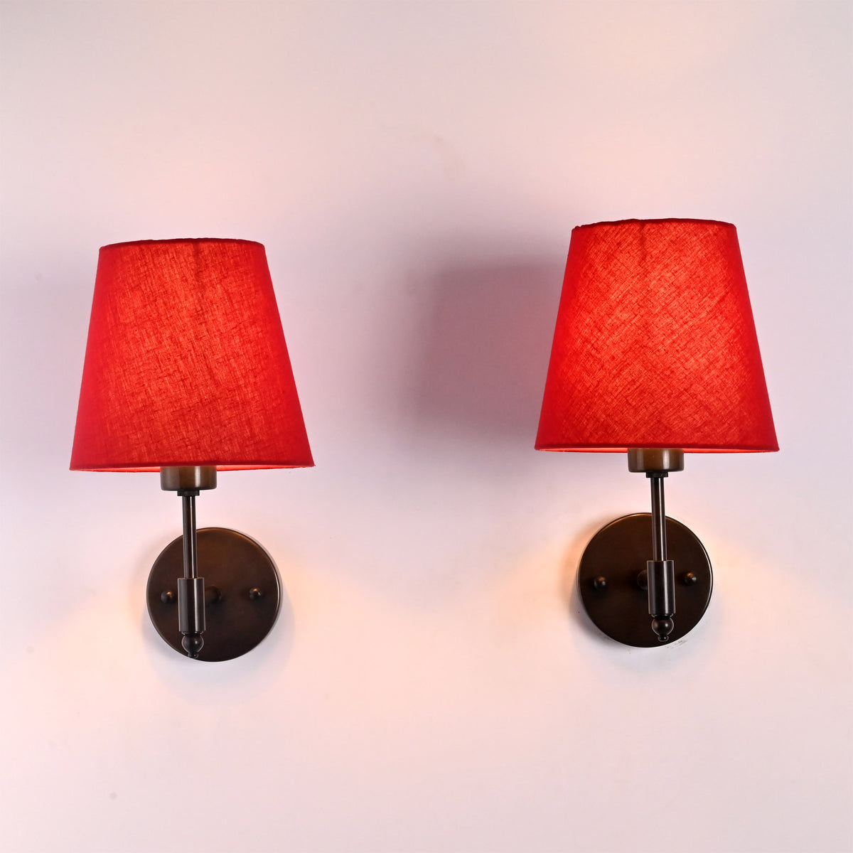 Front pair view of Milan red shade black short wall sconces with red fabric shades and round wall plates.