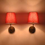 Warm illuminated pair view of Milan red shade black wall sconces creating soft ambient glow on interior wall.