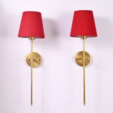 Pair of Milan red shade rod wall sconces with round wall plates and elegant long stem design.