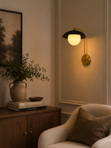 Milan ribbed dome globe wall sconce installed in a warm modern living room with brass and black finish.