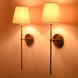 Close up of Milan Shade Rod Wall Sconce showing fabric shade, round backplate, and warm light effect.