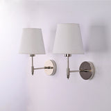 Angled view of two Milan polished chrome wall sconces featuring white tapered fabric shades and solid brass construction for contemporary interiors.