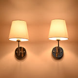 Pair of Milan polished chrome wall sconces with illuminated white fabric shades creating a soft warm ambient glow on the wall.