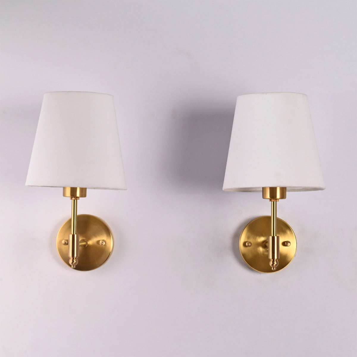 Front view of Milan white fabric shade brushed brass wall sconce featuring a handcrafted brass frame with a tapered white fabric shade.