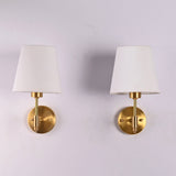 Front view of Milan white fabric shade brushed brass wall sconce featuring a handcrafted brass frame with a tapered white fabric shade.