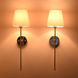 Evening illuminated view of Milan white shade chrome rod wall sconces with warm shade glow and elegant finish.