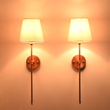 Close front view of Milan white shade copper sconces with bright shade glow and round wall plates.