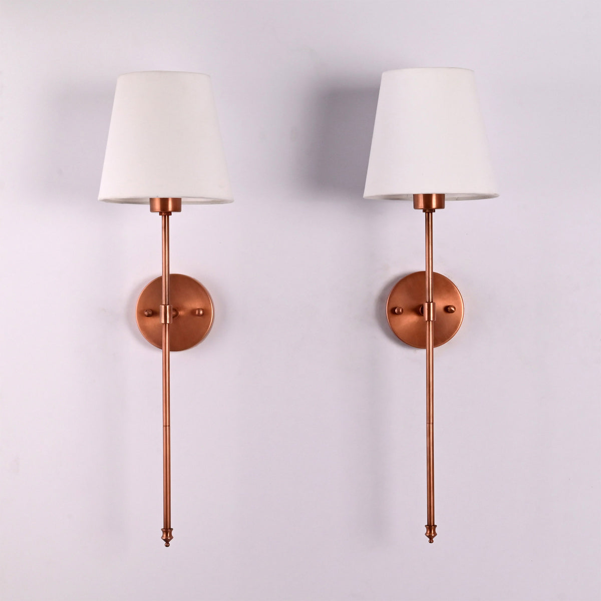 Front view of Milan white shade copper rod wall sconces with slim vertical frame and round backplates.