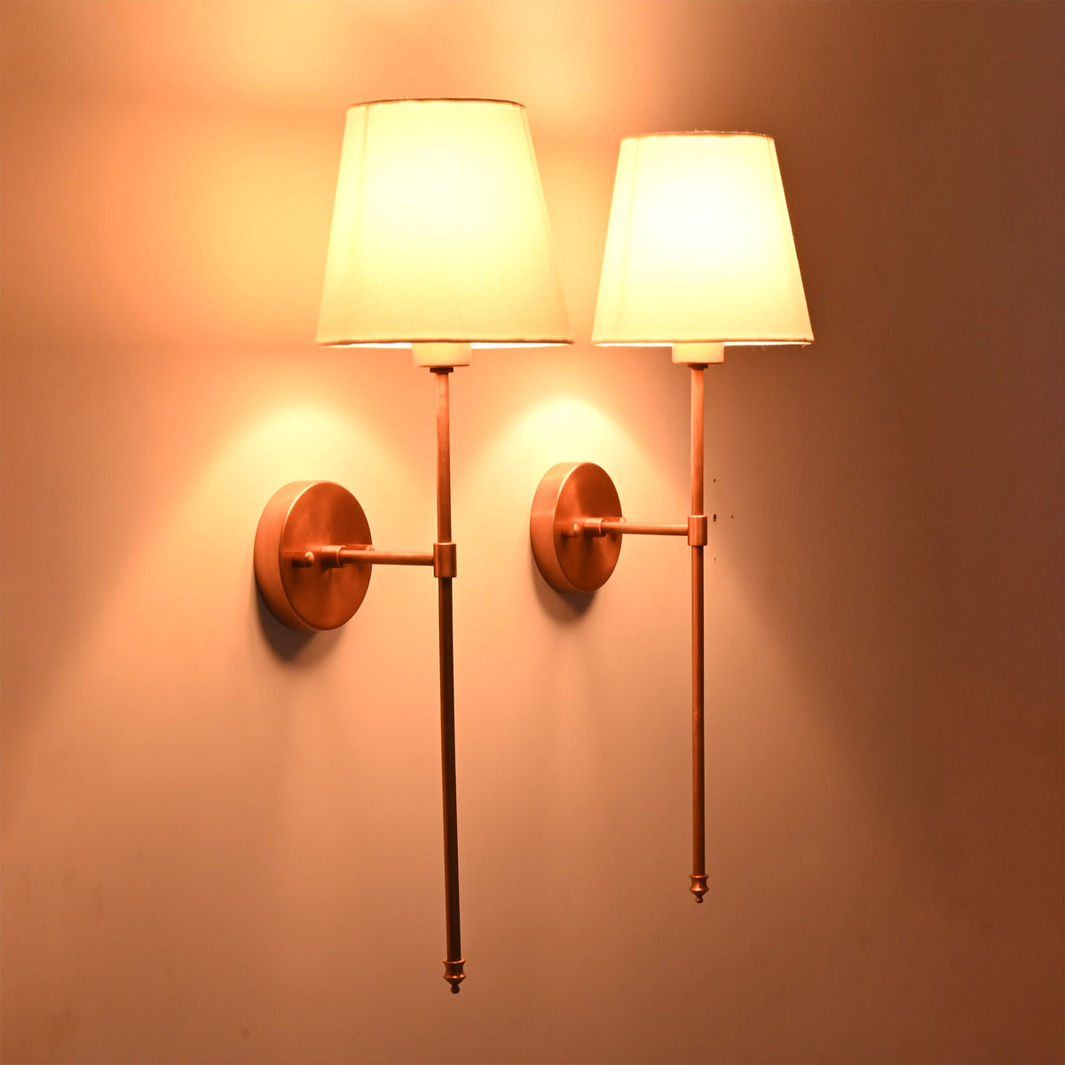 Side angle view of Milan white shade copper wall sconces showing warm light and 8 inch projection