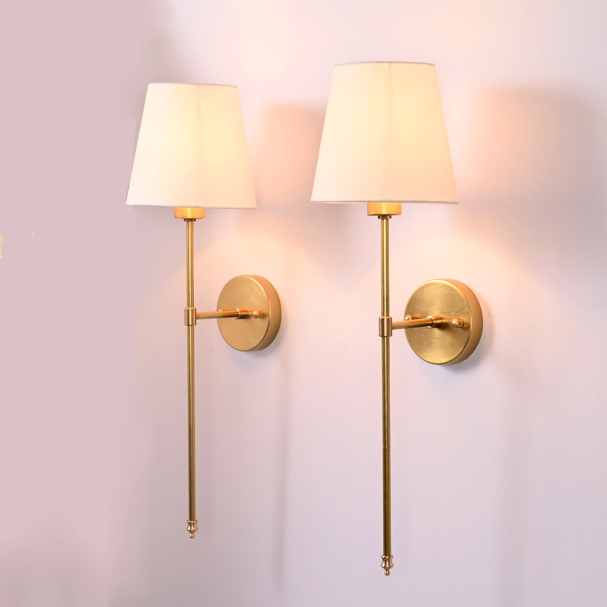 Front view of two white shade rod wall sconces with round backplates and elegant long stems.
