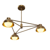 Three-light modern brass chandelier with dome shades and geometric arms, showcasing minimalist mid-century design and warm ambient illumination.