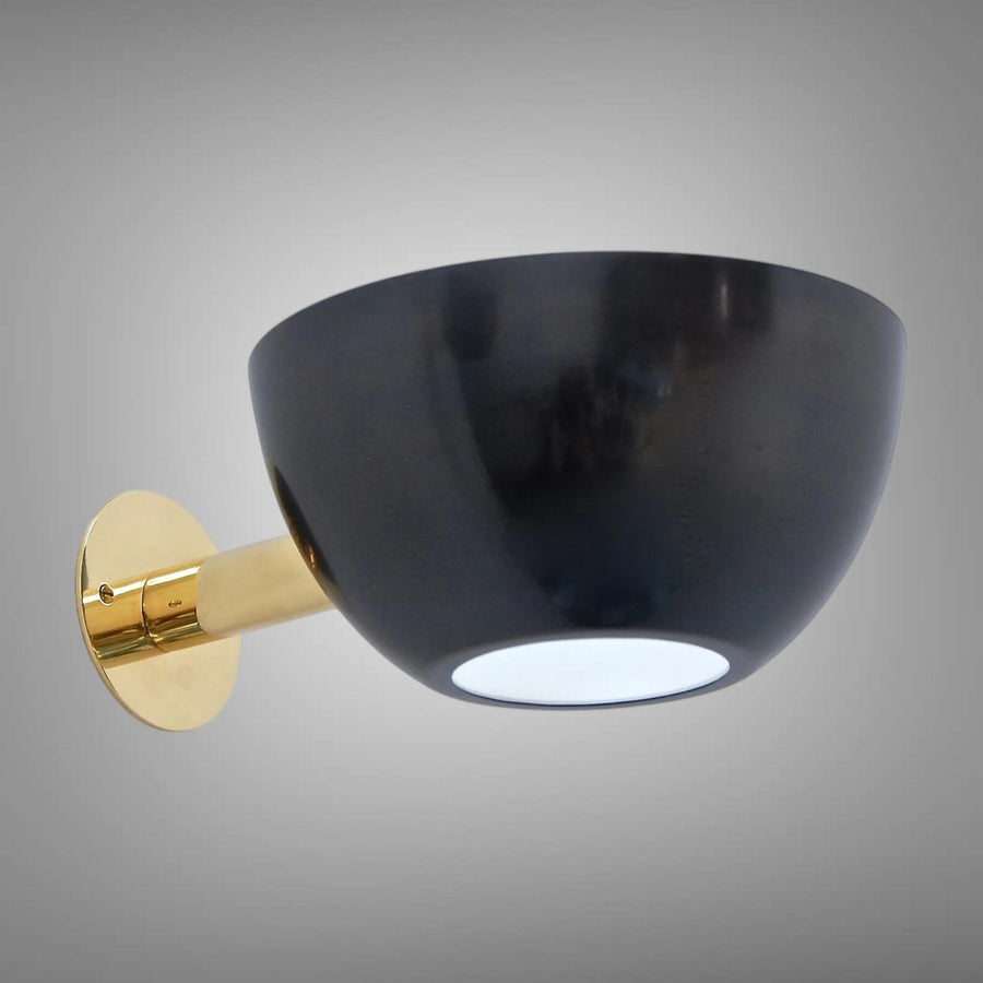 Modern bowl wall sconce with glossy black metal shade and polished brass backplate and arm on a gray background.