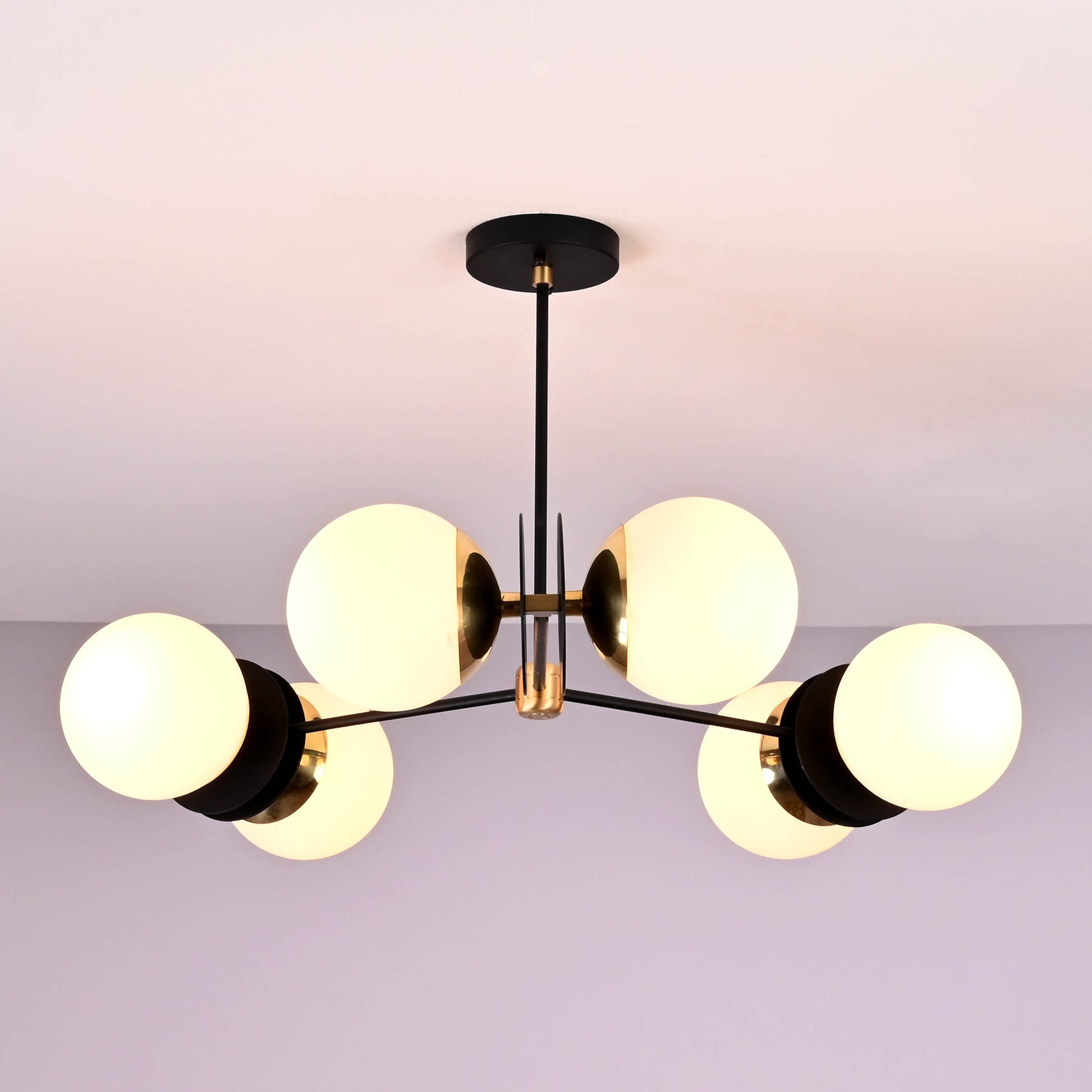 Ceiling-mounted 6-light chandelier with brass accents and matte black frame, featuring round opal glass globes for a modern minimalist look.