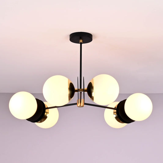 Ceiling-mounted 6-light chandelier with brass accents and matte black frame, featuring round opal glass globes for a modern minimalist look.