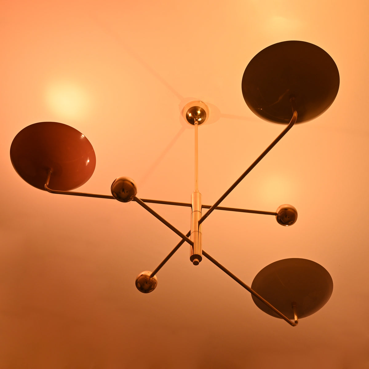 Brass chandelier with colorful shades casting soft golden glow, elegant modern design for ambient interior lighting.