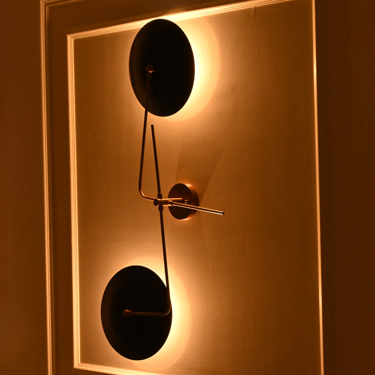 Nashville brass and navy blue wall sconce photographed from an angle with soft warm backlighting and dramatic evening ambiance.