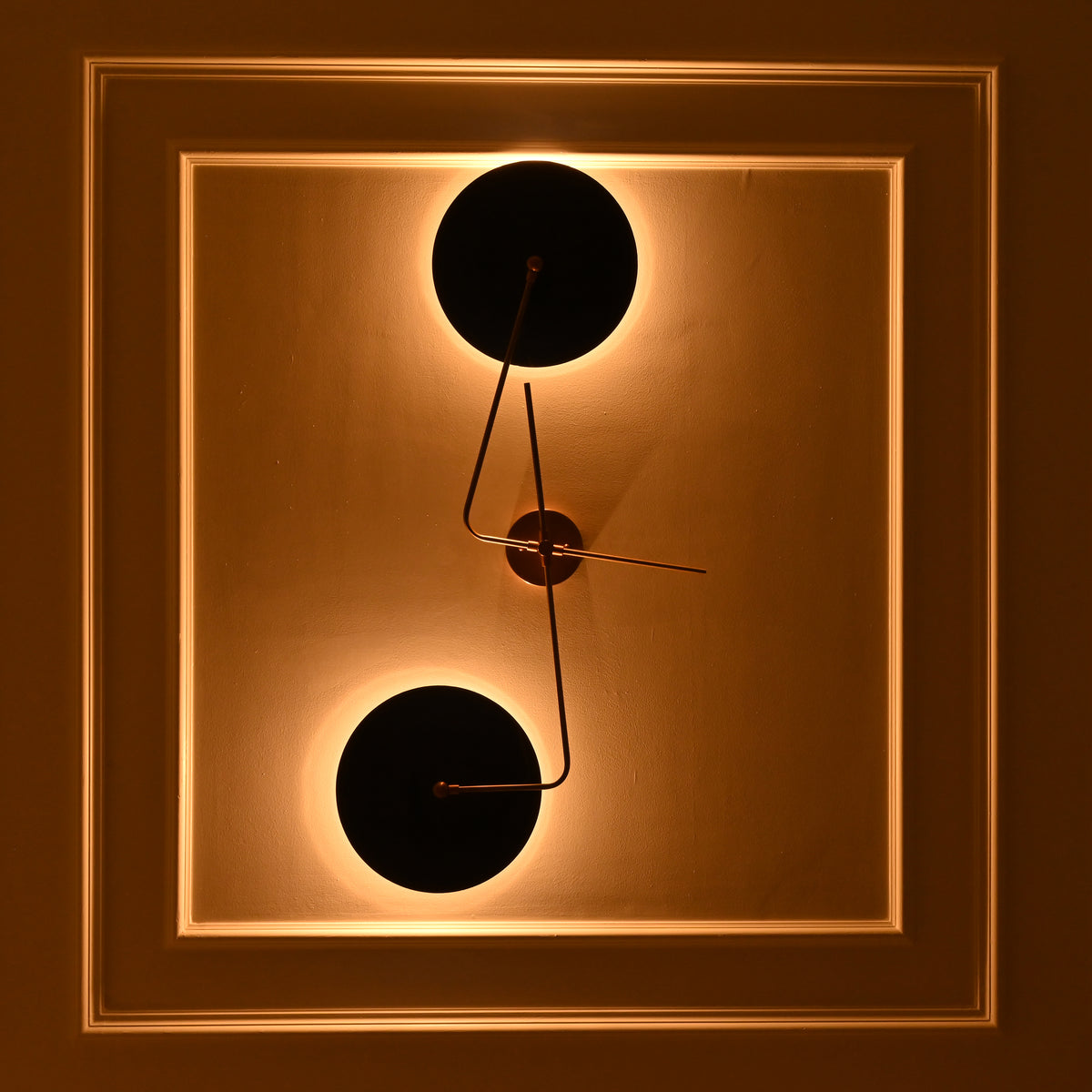 Front view of Nashville two-light geometric wall sconce with circular navy blue shades creating glowing halos against an elegant paneled wall.
