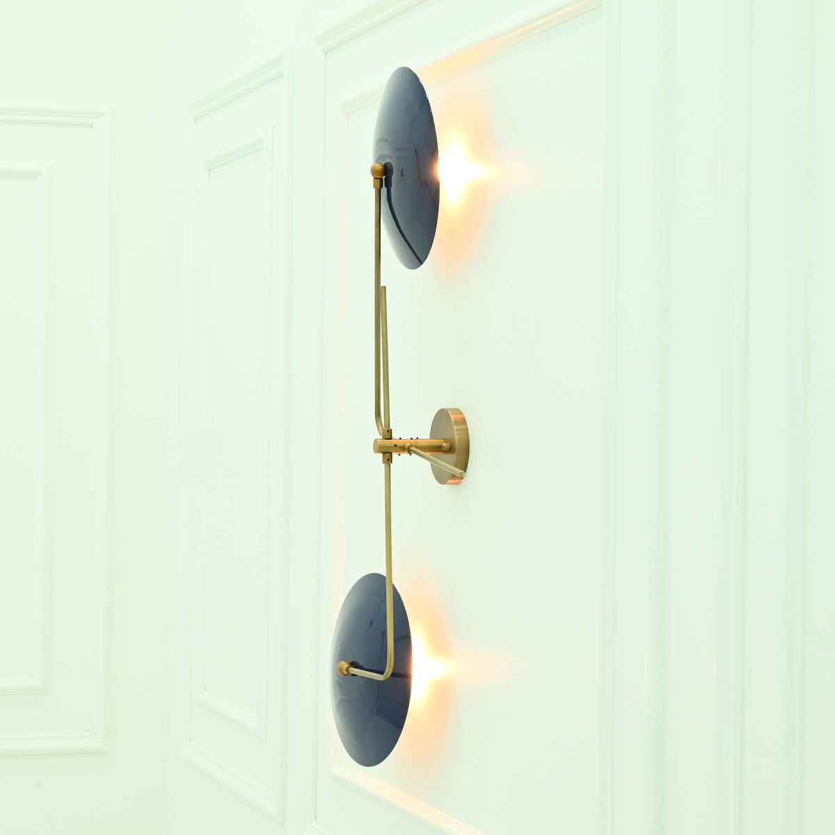 Side profile of Nashville modern wall sconce highlighting curved navy blue metal shades, slender brass framework, and wall-mounted construction.