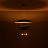 Noir Tiered Disc Chandelier displayed in a dark setting with warm lower bulbs and ambient glow.