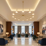Full view of Orion 12 light multi-arm chandelier with ivory cone shades and Mid-Century Modern brass frame