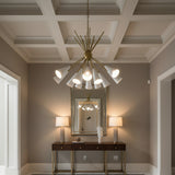 Orion 10 light chandelier with white tapered cone shades, brass arms and sculptural starburst design on a white background.