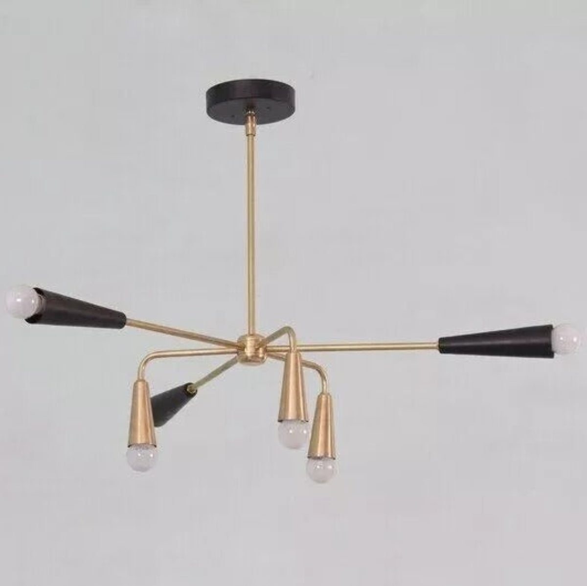 Side view of the Osaka 6-light sculptural chandelier featuring elongated black cone holders, downward-facing brass-tone shades, exposed white bulbs, and a central suspension rod.