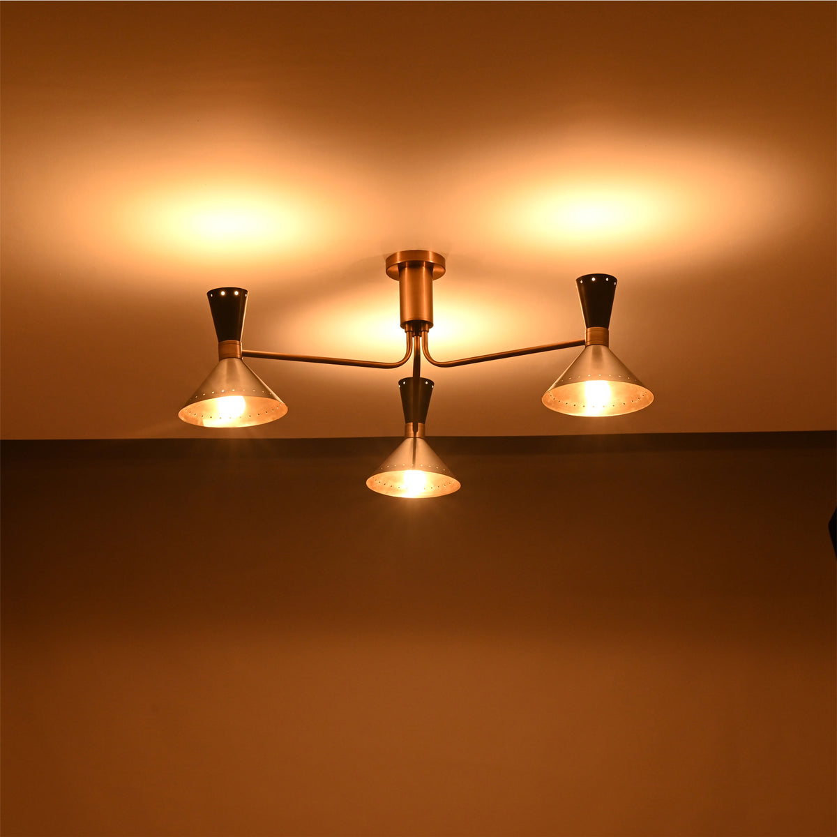 Oslo Cone Arm Chandelier glowing warmly in low light with three illuminated cone shades.