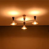 Oslo Cone Arm Chandelier glowing warmly in low light with three illuminated cone shades.