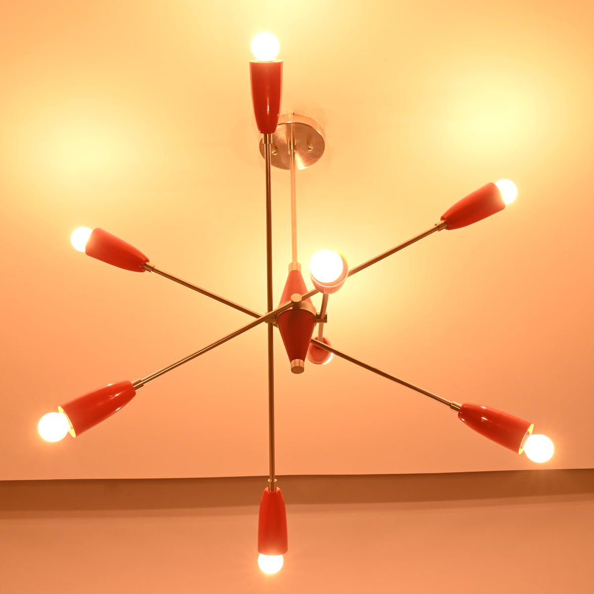 Bottom illuminated view of the Oslo Modern Cone Sputnik Chandelier featuring exposed globe bulbs, red cone shades, brushed nickel arms, and geometric Mid-Century Modern design.