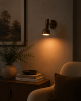 Lifestyle view of Oslo modern polished nickel bedroom wall sconce installed above a wooden sideboard, providing warm ambient and reading light in a contemporary interior.