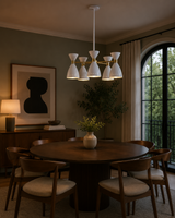Oslo 5 light perforated cone chandelier illuminated above a round dining table in a warm modern dining room.