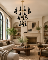 Oslo 20 light tiered chandelier illuminating a warm Mid-Century Modern living room with black cone shades and brass accents.