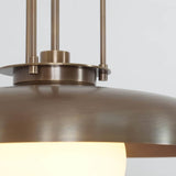 Close-up of the Palermo pendant light showcasing its brushed bronze-tone metal finish, curved dome shade, decorative suspension rods, and softly illuminated white globe.