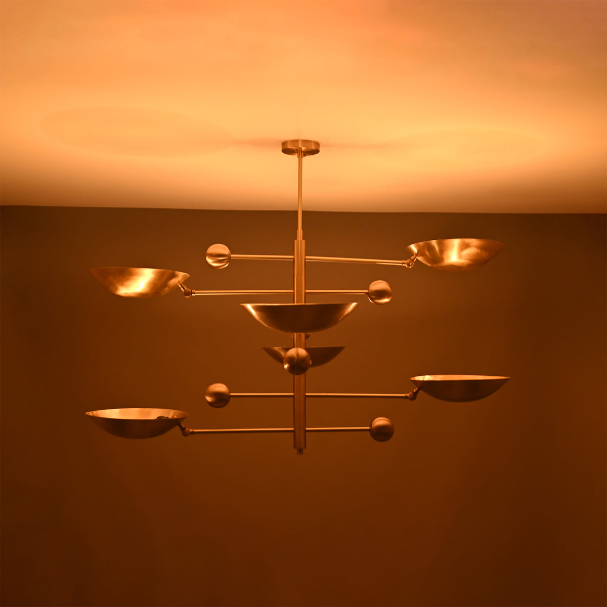 Front view of Palermo Orbital chandelier glowing warmly with layered disc shades and Mid-Century Modern styling.