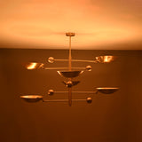 Front view of Palermo Orbital chandelier glowing warmly with layered disc shades and Mid-Century Modern styling.